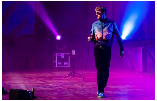 James Acaster on stage with purple lights